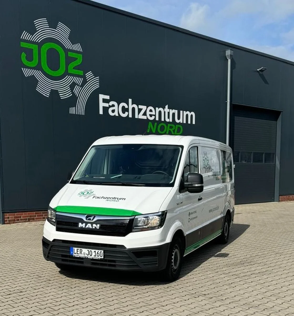Weißer MAN-Servicetransporter des JOZ Fachzentrum Nord vor der Firmenhalle mit JOZ-Logo auf der Fassade